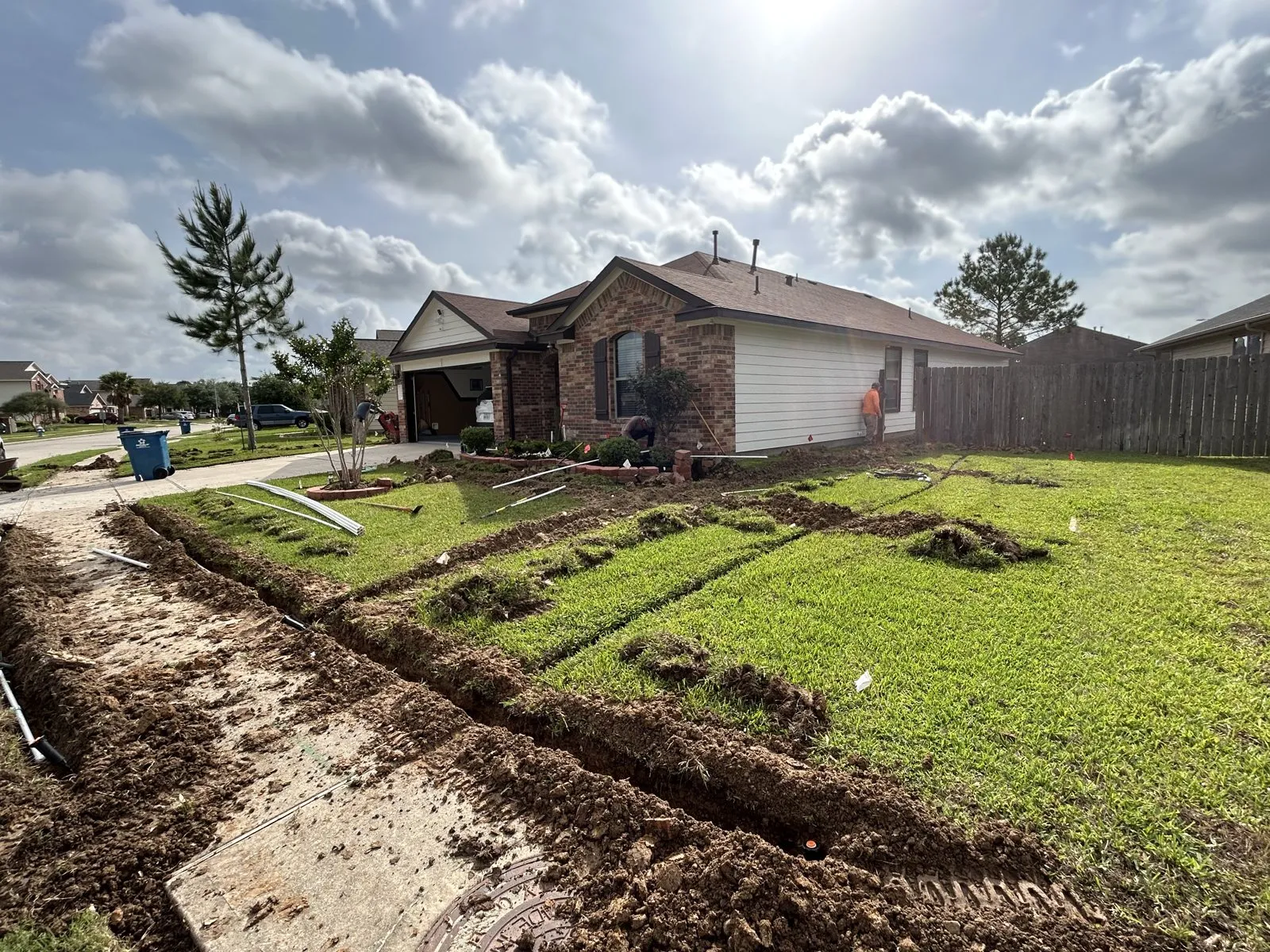 Open installation trenches across a front lawn during work