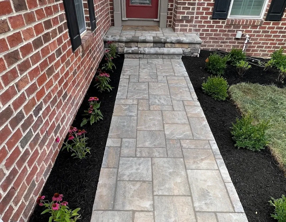 Paver entry path and shallow steps beside flowering plants and fresh mulch