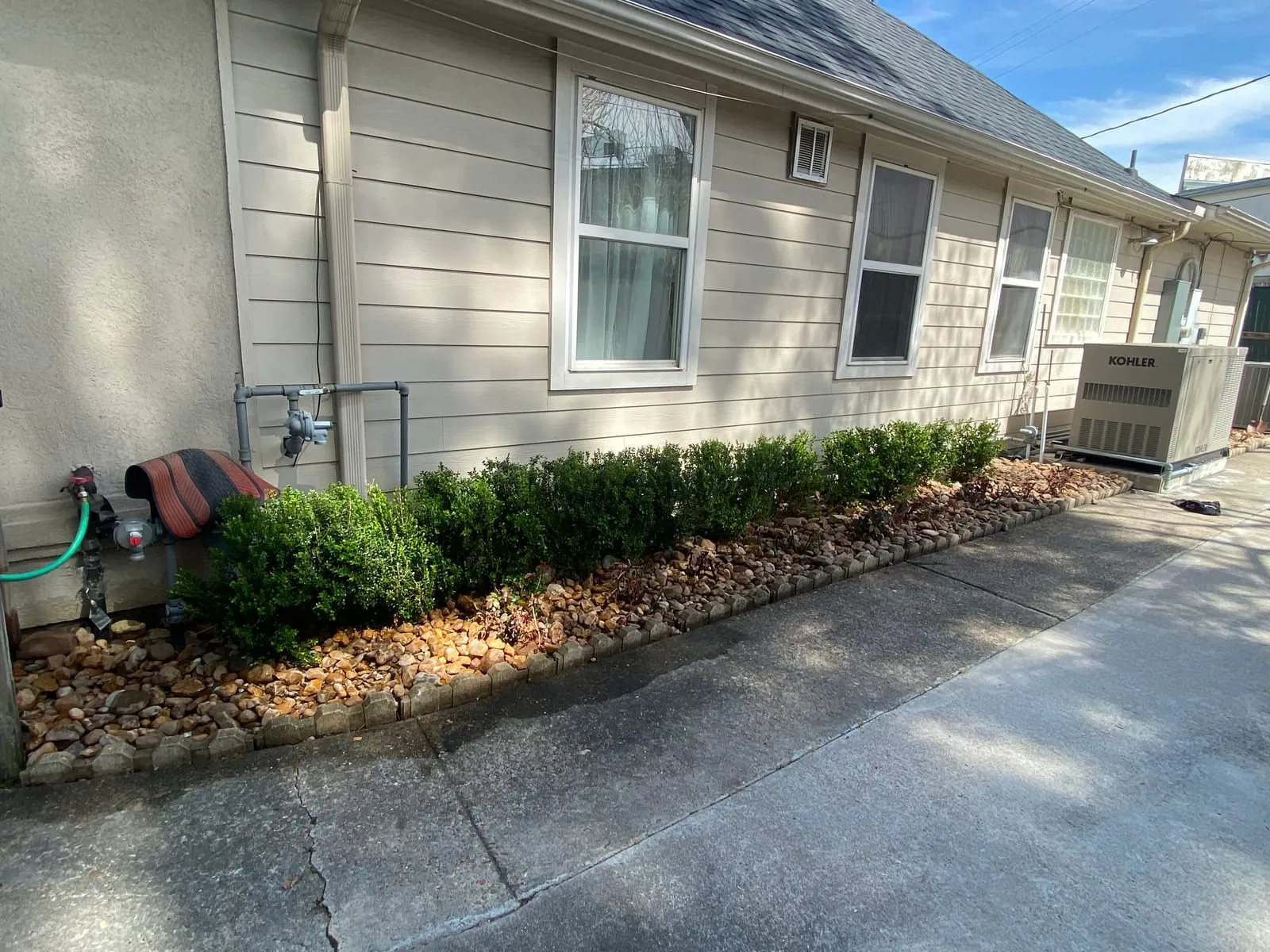 River-rock planting bed with a low block border beside a home