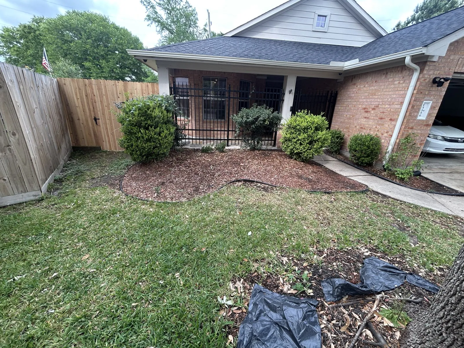A cleared planting bed and shrubs beside a covered front porch